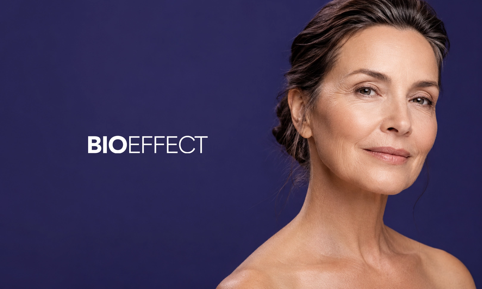 Portrait d'une femme d'âge moyen avec une peau éclatante et un léger sourire sur un fond bleu foncé avec le texte BIOEFFECT en blanc à gauche.