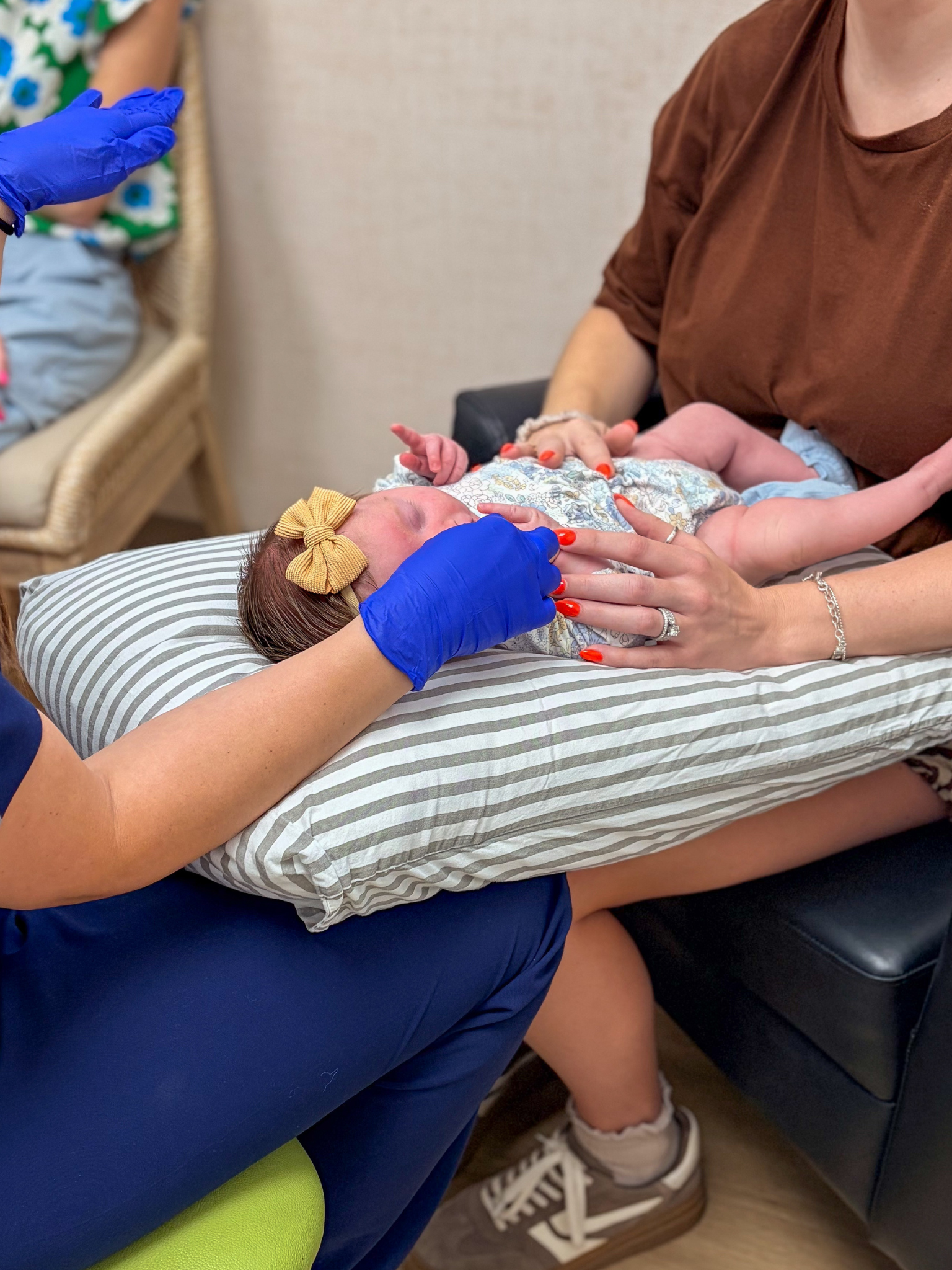 Infant being gently evaluated with a caregiver nearby.