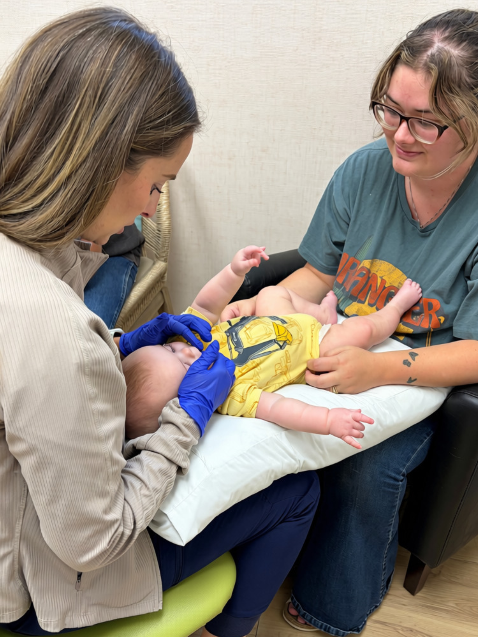 Parkview provider evaluating an infant while a caregiver supports the baby.