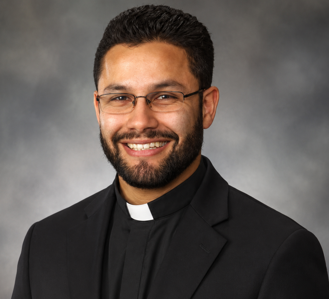 Father Felipe Vives smiling in clerical collar staff portrait
