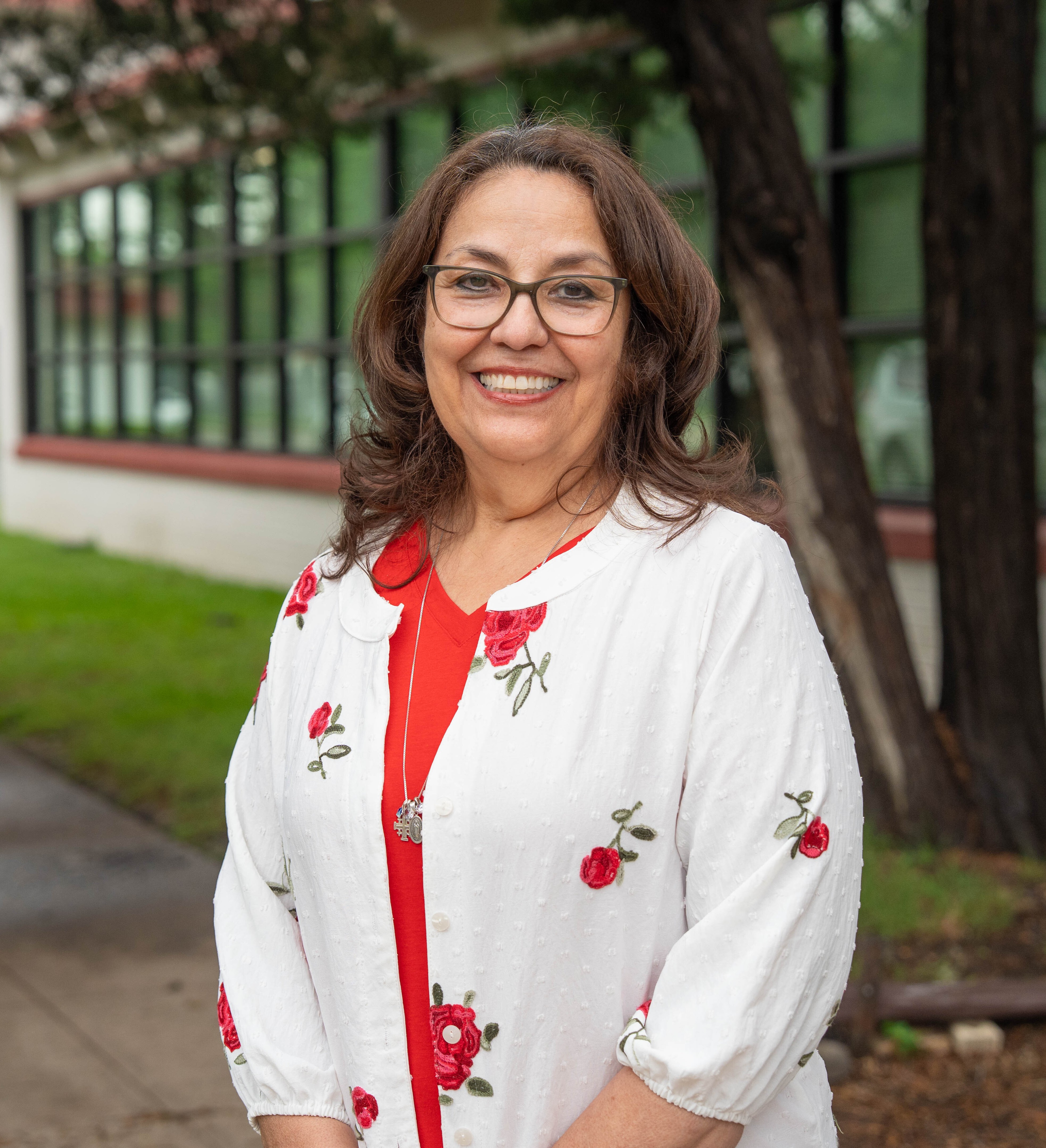 Linda G. Santos smiling outdoors in front of school building