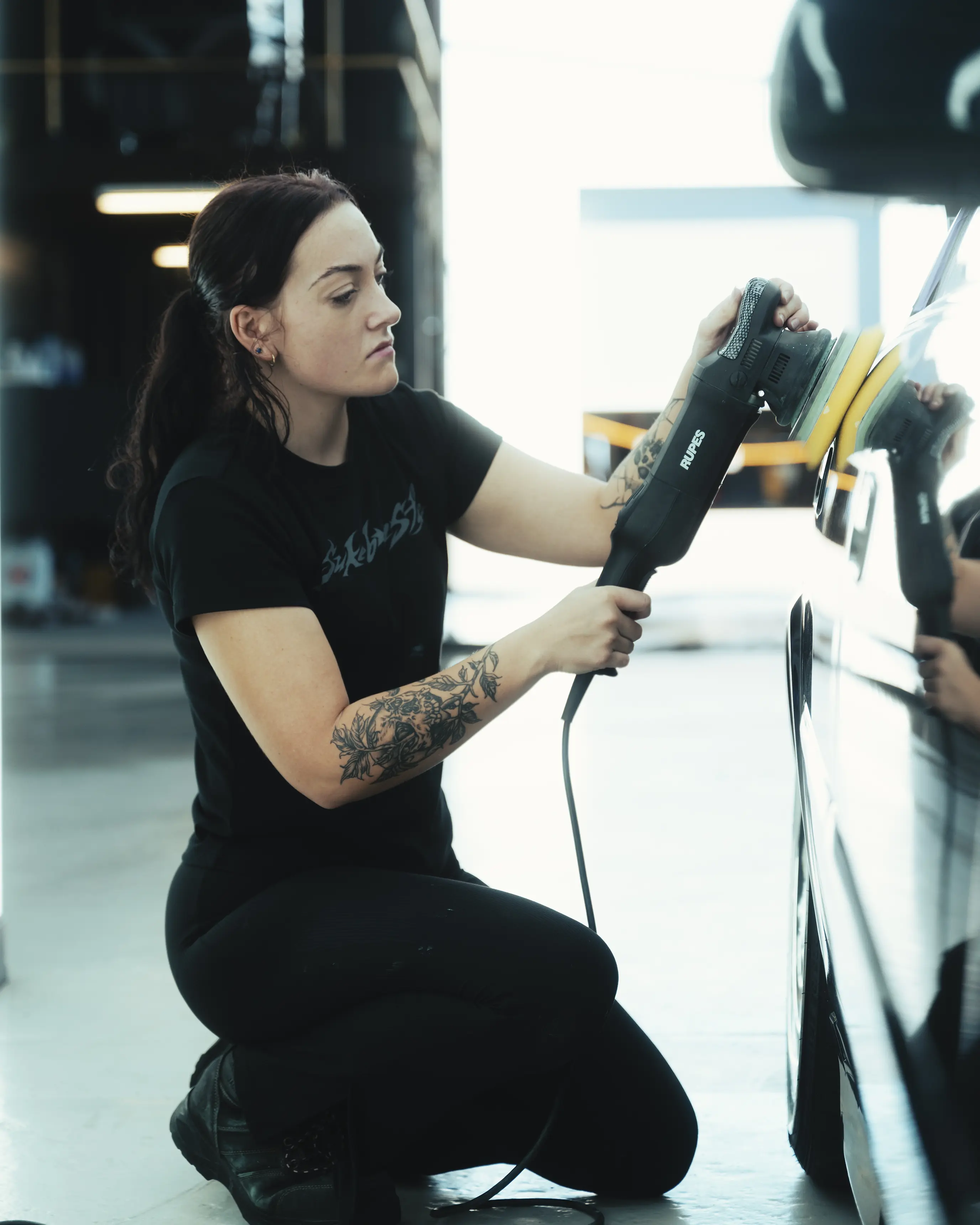 Young lady buffing the side panel of an EH Chaser in the Ghostline Workshop
