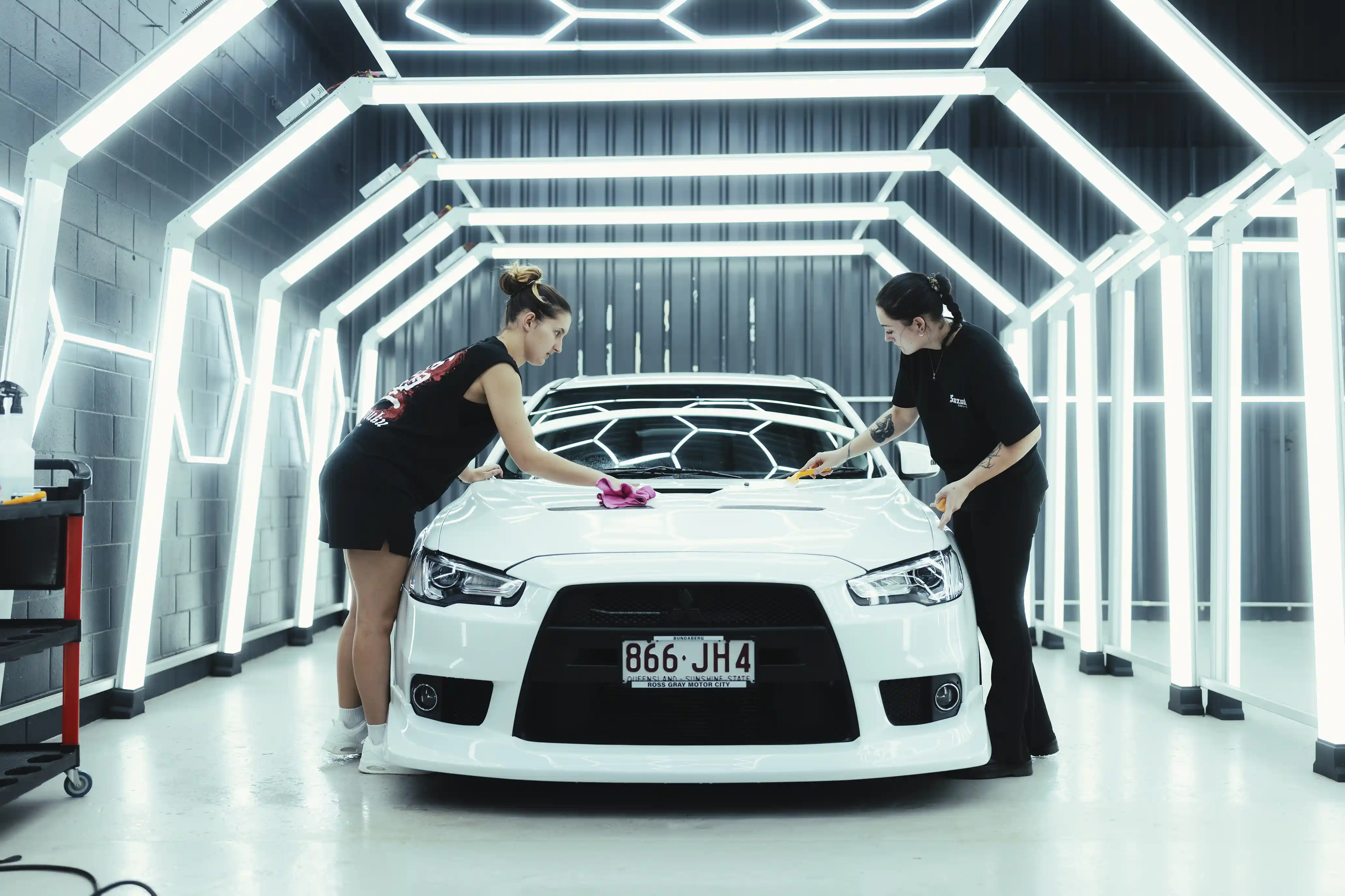 White Mitsubishi Evo being wiped down under paint inspection lights