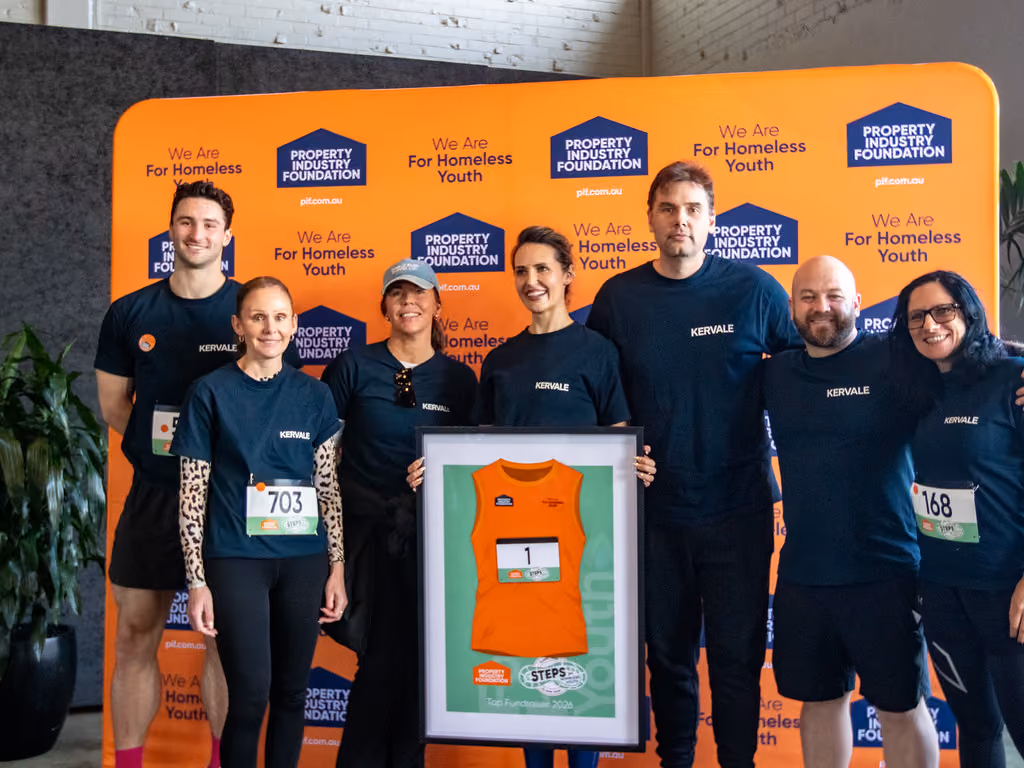 Seven people in Kervale shirts stand in front of an orange Property Industry Foundation backdrop.