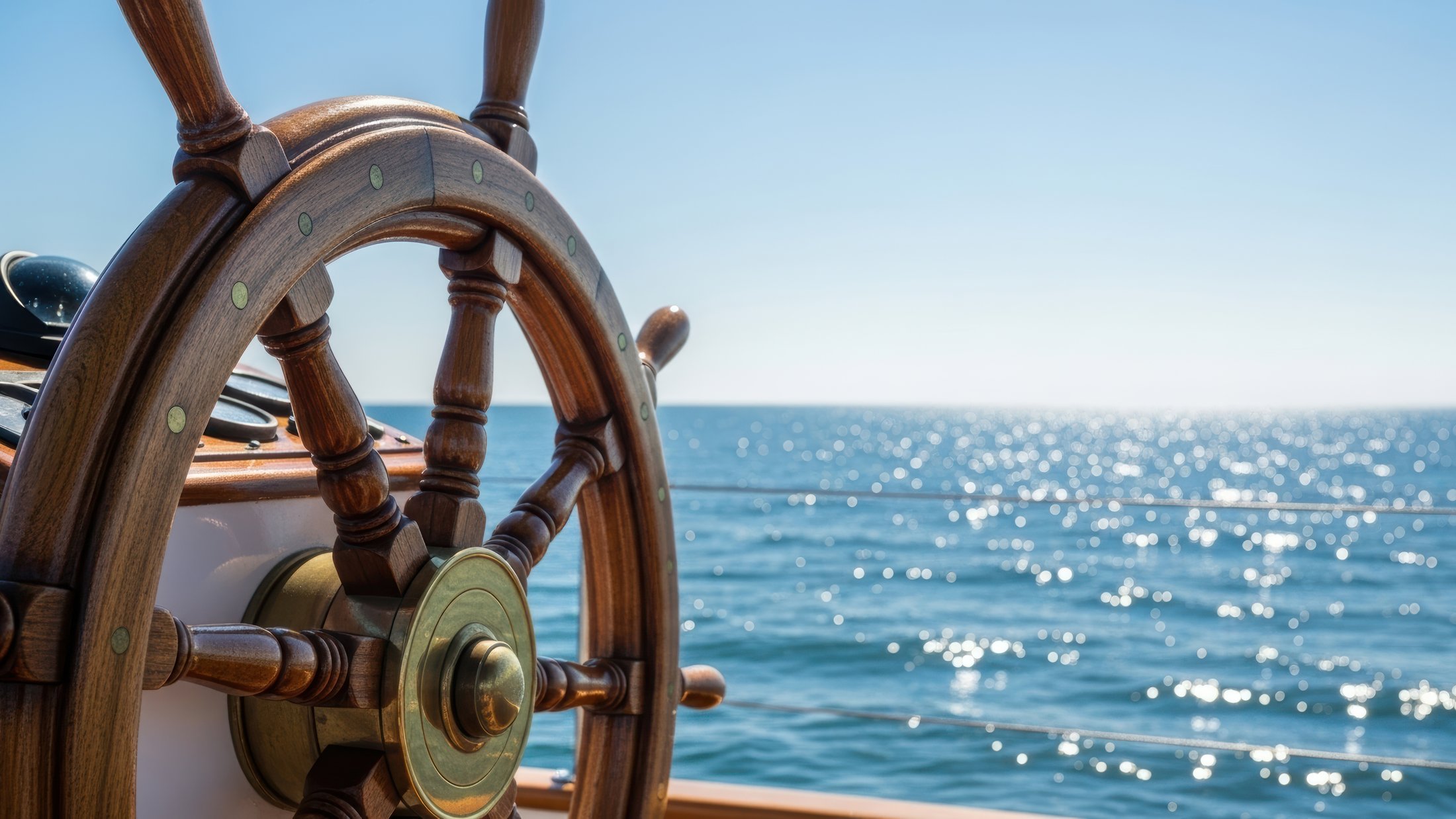 Ship's wheel at the helm, looking out over open water