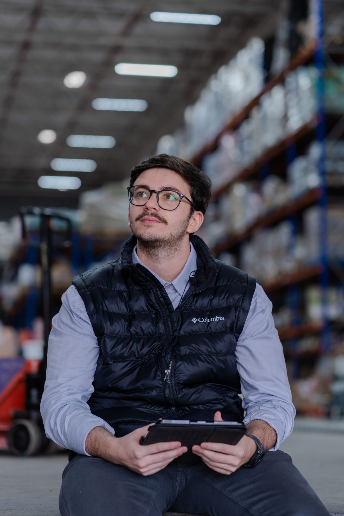 A warehouse worker using a tablet in an aisle