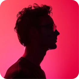 Silhouette of a person with curly hair and glasses against a vibrant pink background.
