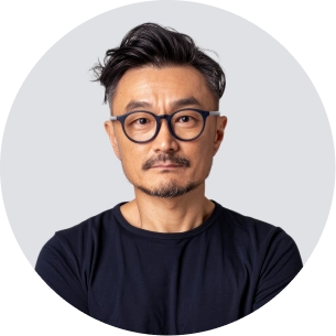 Man with glasses, short dark hair, and mustache wearing a black shirt against a light background.