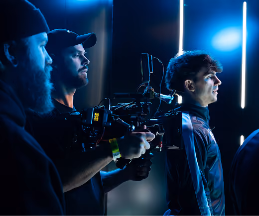 Film crew operating a camera rig on a blue-lit studio set