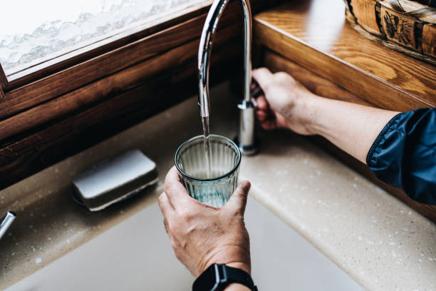 A glass being filled with water from a kitchen tap
