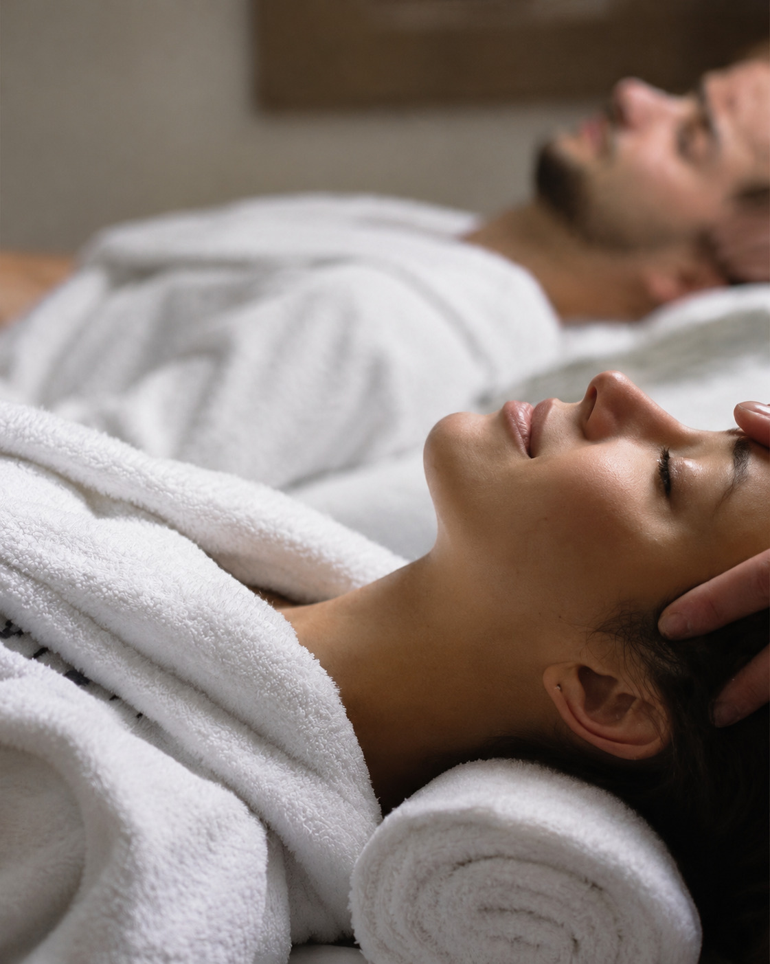 Two people in robes lying side by side during a couples treatment, with hot towels