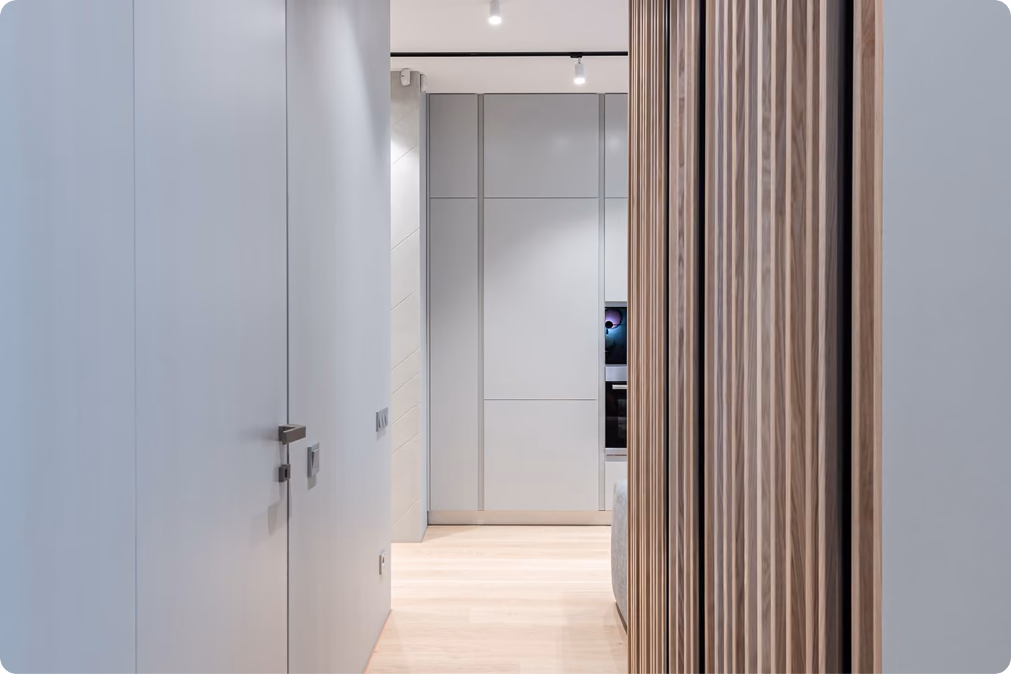 Minimalist hallway with light wood floor, gray closed door on left, and vertical wooden slat wall on right.