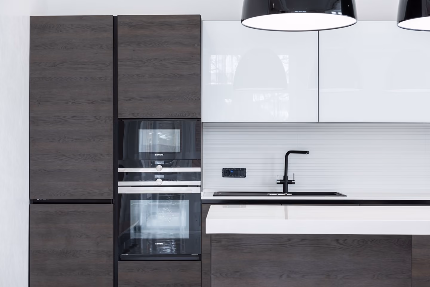 Modern kitchen with dark wood cabinets, built-in Siemens oven and microwave, white countertop, and black faucet.