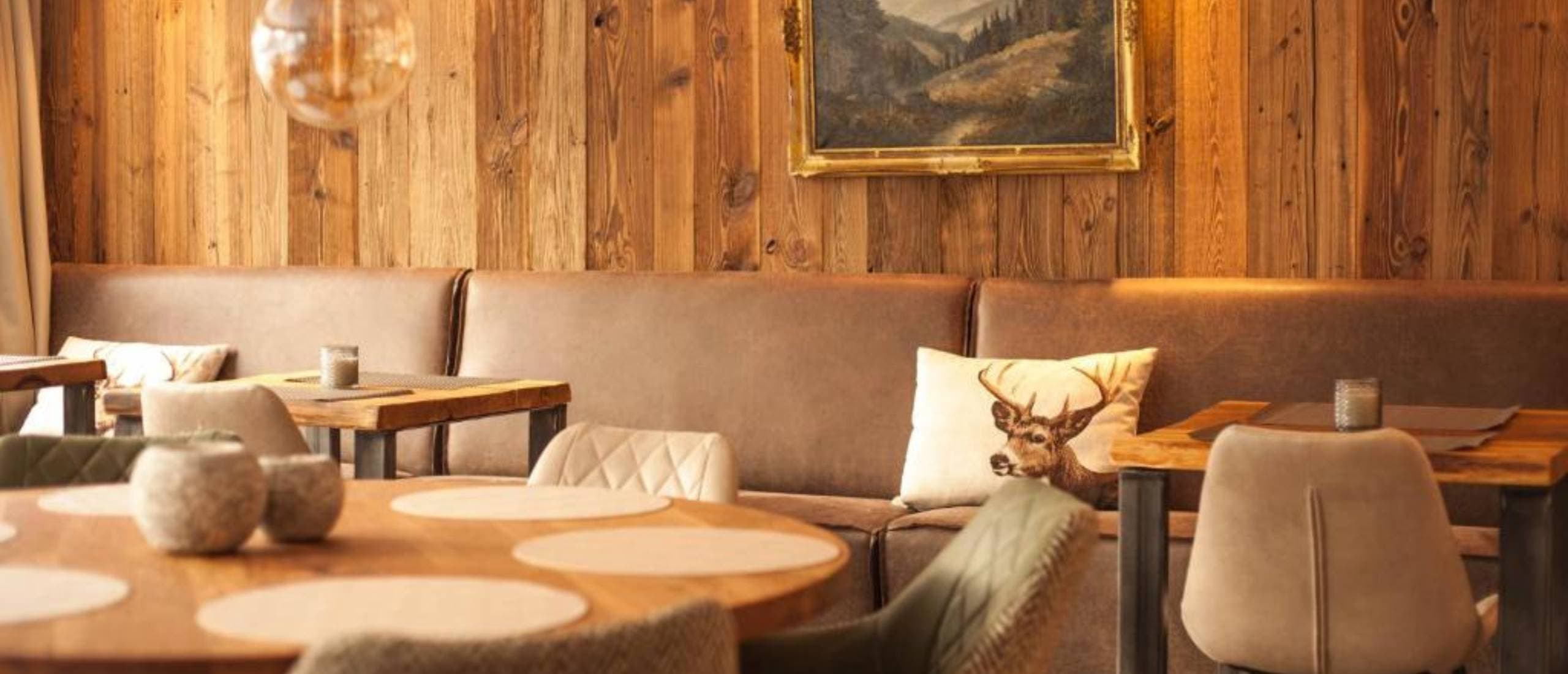 Gemütlicher Restaurantbereich im Harz Hotel Iris mit Holzwänden, Lederbänken und Hirschmotiv-Kissen
