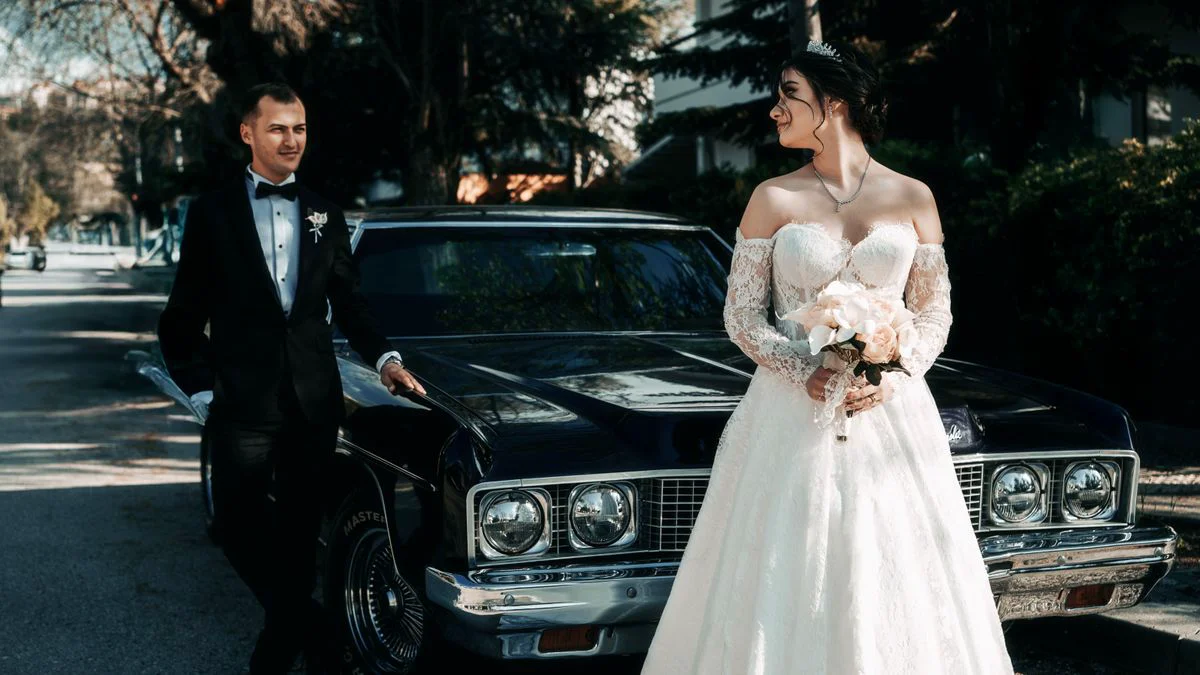 Vintage wedding car decorated with ribbons outside a venue