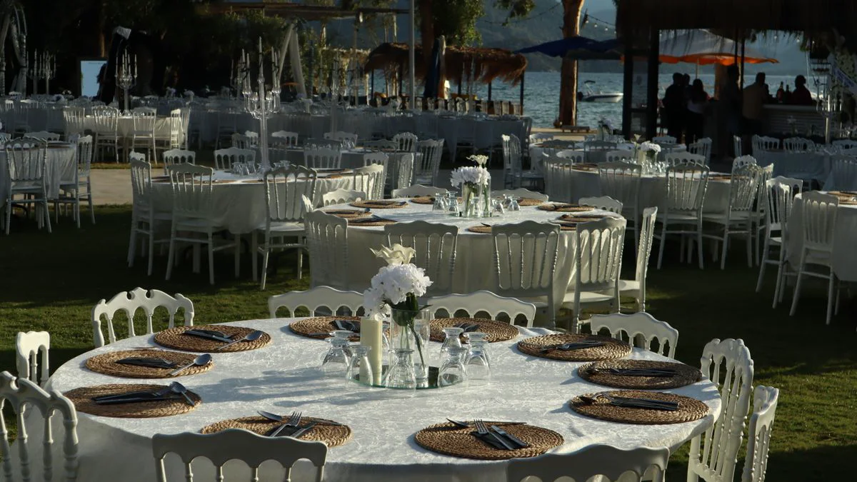 Wedding reception tables arranged beside large windows overlooking water