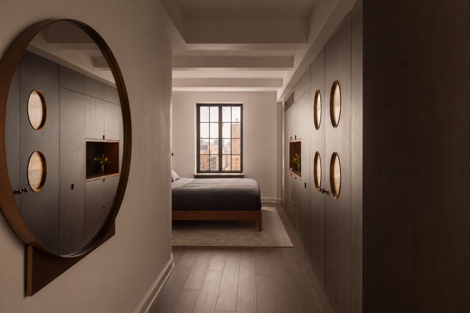 Modern bedroom with large window, dark built-in closets, and round mirror reflecting closet details.