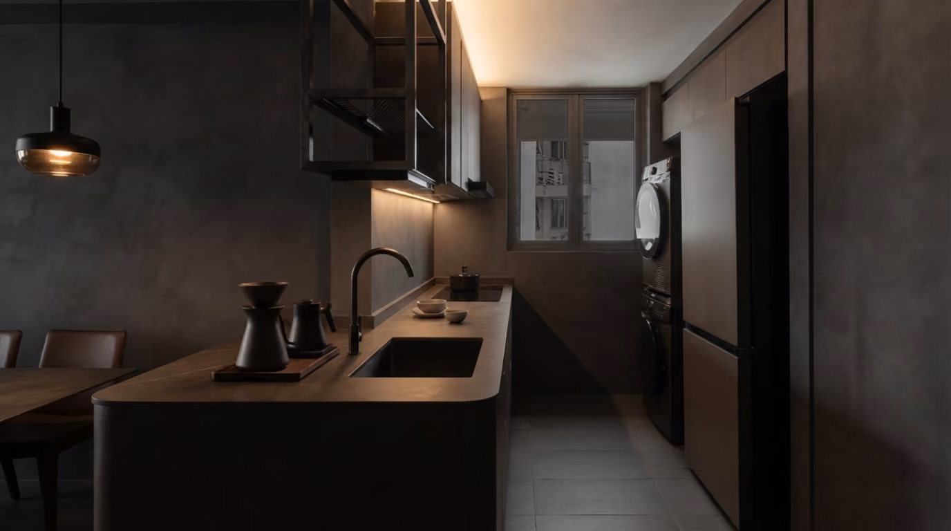 Dark luxury kitchen with matte black fixtures, chandelier, built-in appliances, and dim ambient lighting.