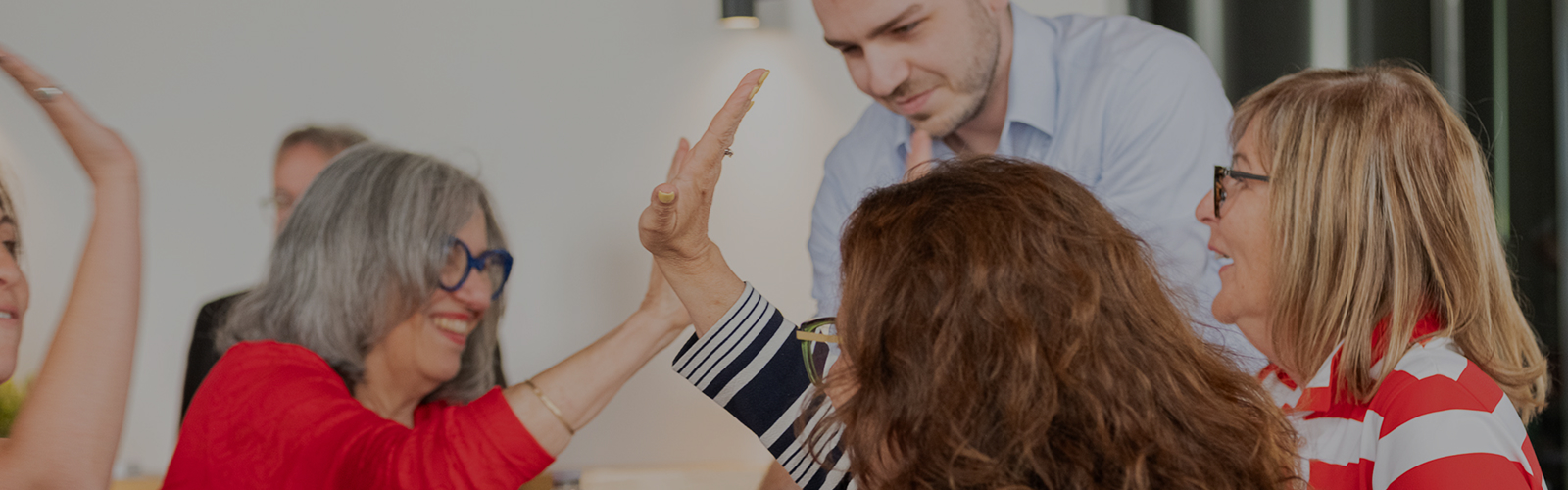 Des collègues souriants se faisant un high five lors d'une réunion informelle en bureau.