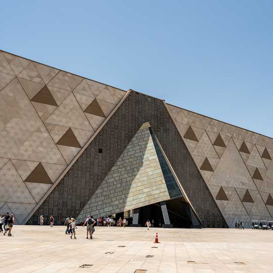 Interior of a large building with walls decorated in golden hieroglyphs and a patterned yellow wall.