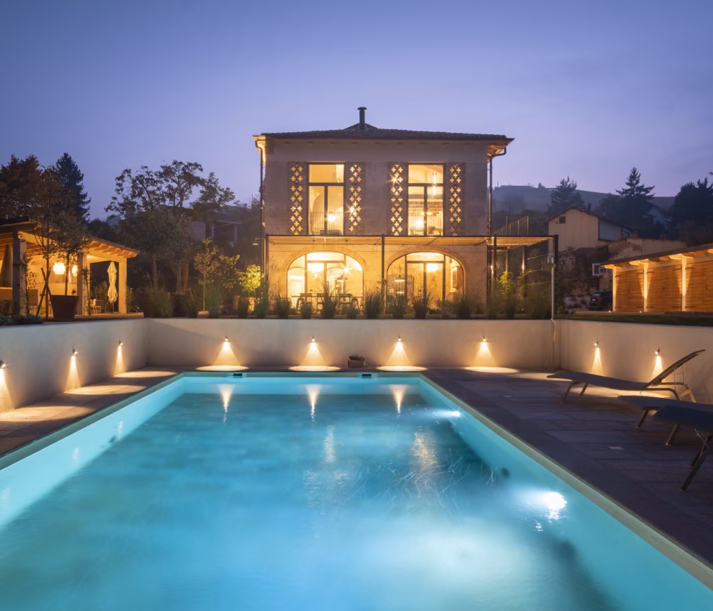 Illuminated house behind a swimming pool.