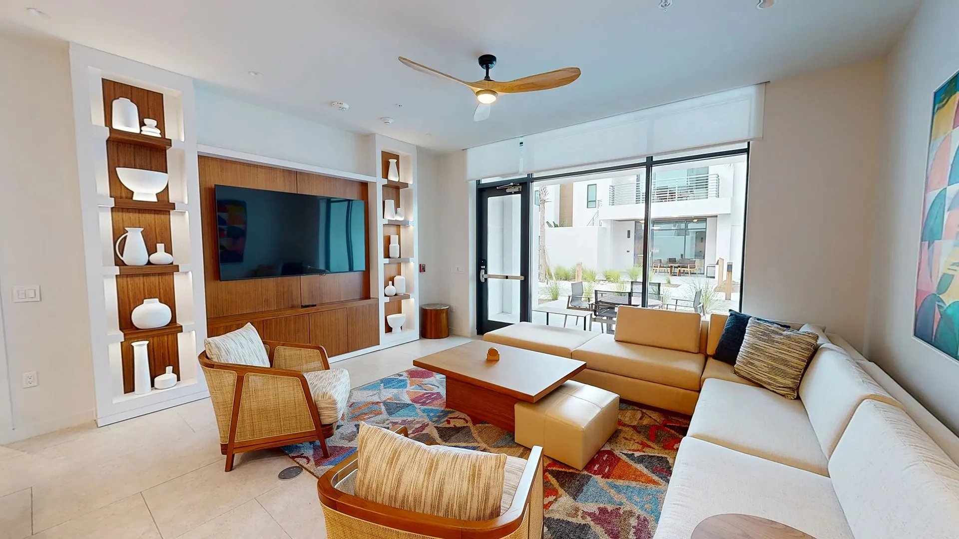 Bright living room with sectional sofa, two armchairs, wooden coffee table, and wall-mounted TV.
