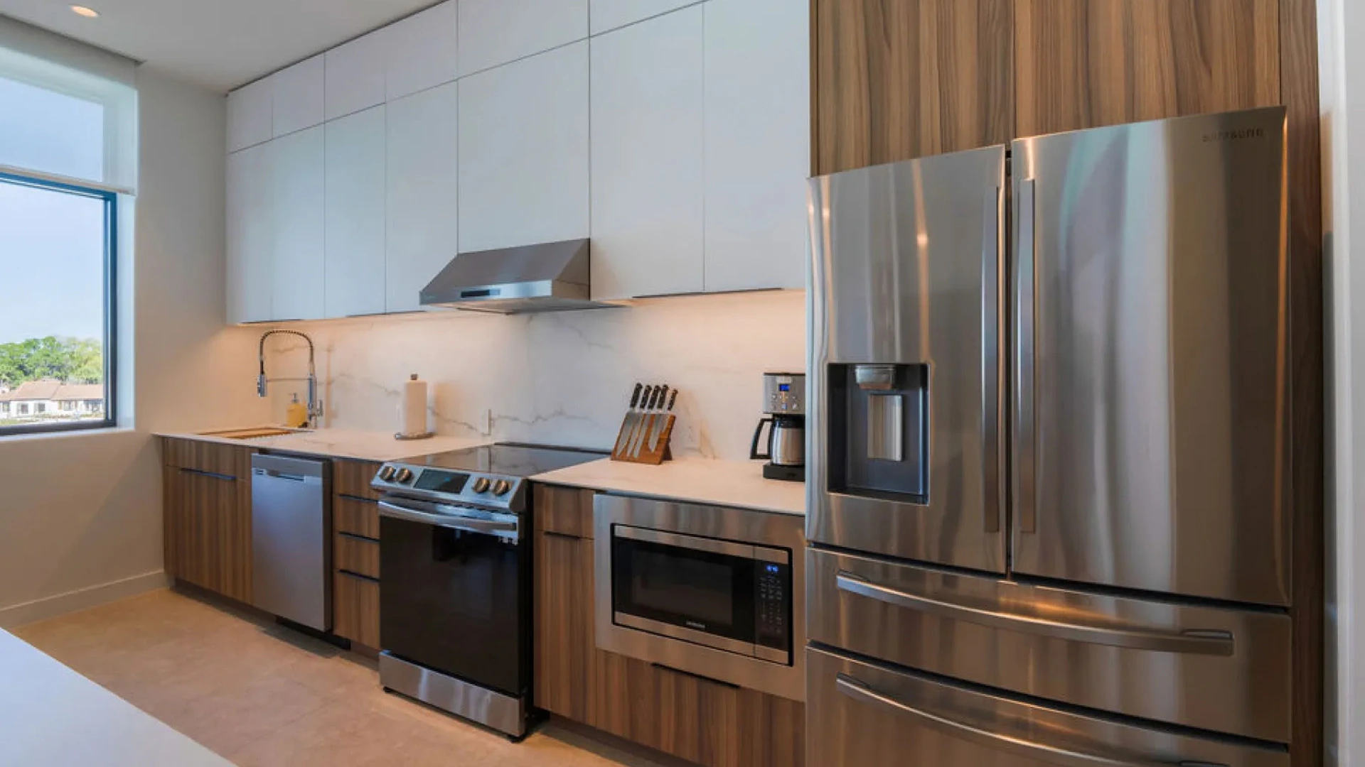 Modern kitchen with stainless steel refrigerator, stove, microwave, dishwasher, and wooden cabinets.