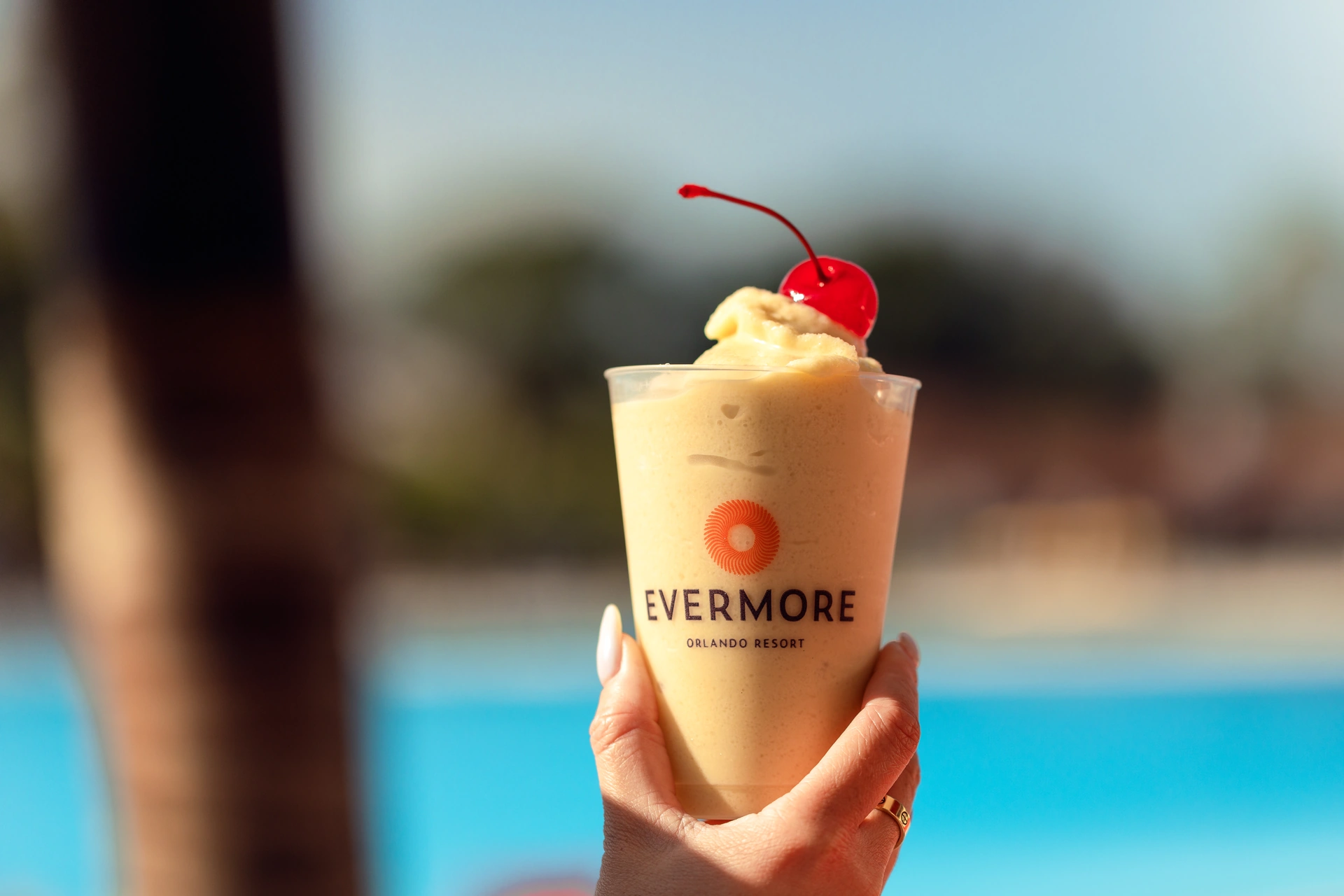 Hand holding a creamy frozen drink topped with a maraschino cherry at Evermore Orlando Resort.