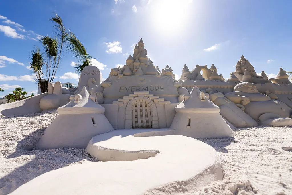 Detailed sandcastle on a beach with the word Evermore carved above a small doorway.