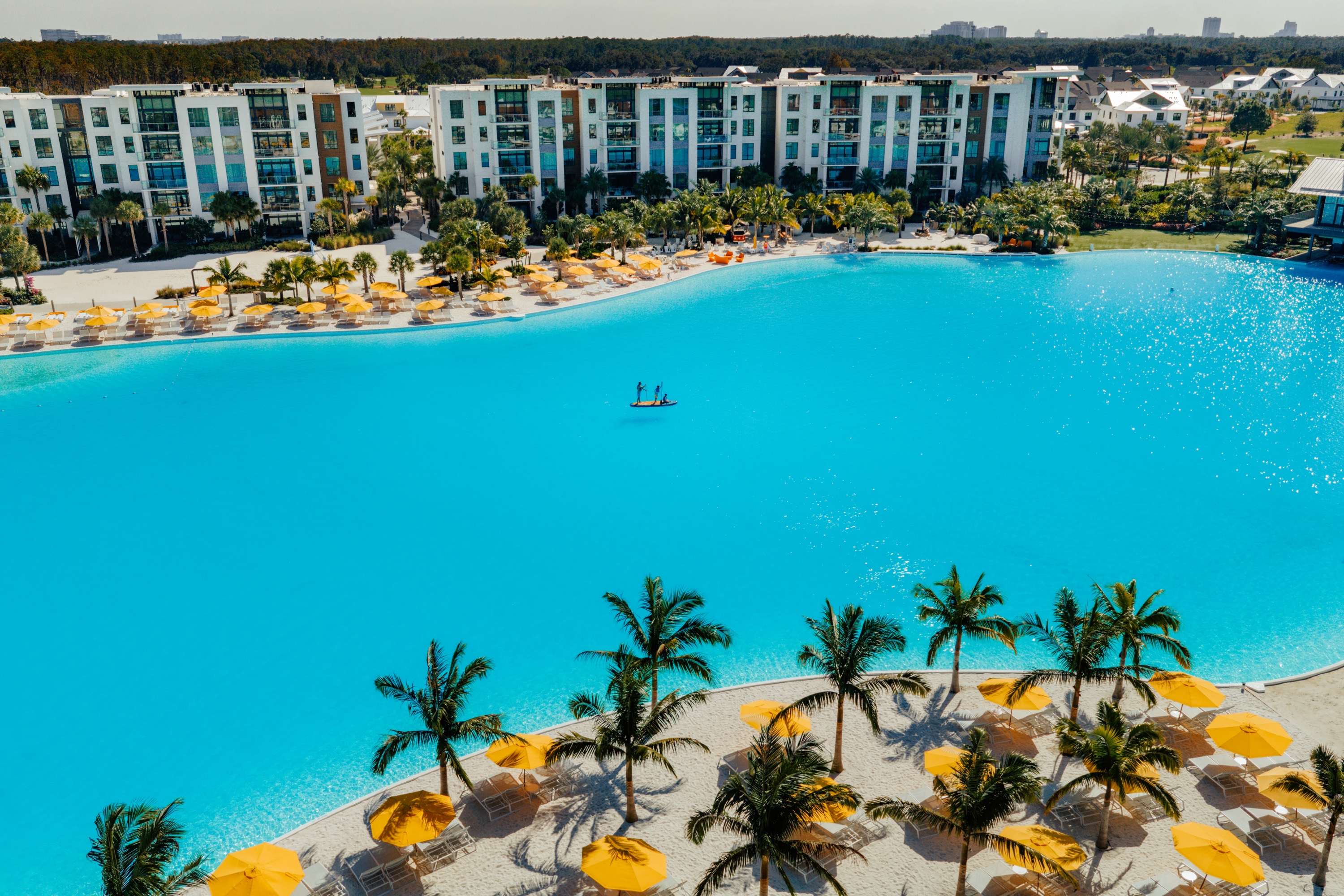 Aerial drone view of Evermore's crystal lagoon with paddleboarders and the Tower Flats buildings