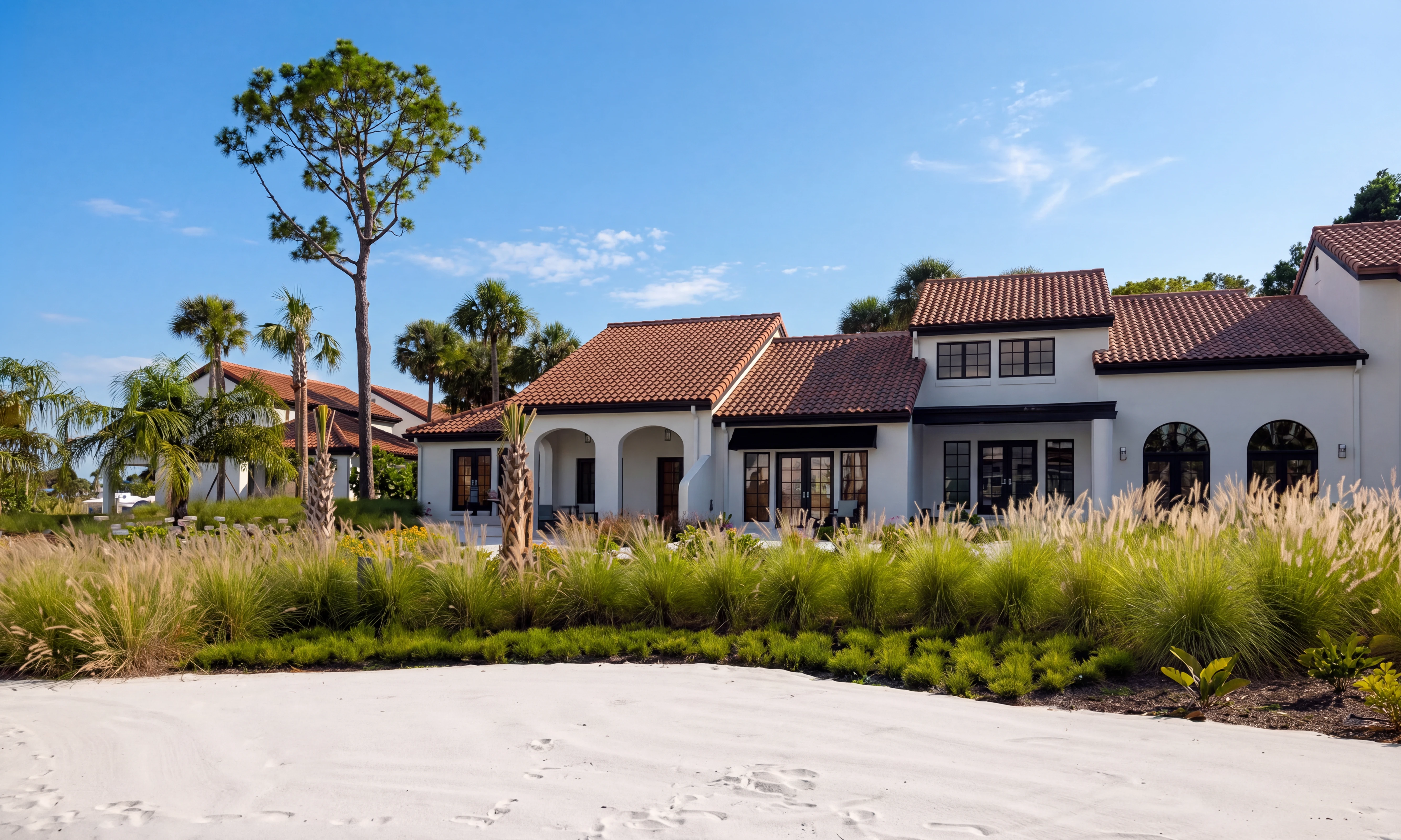 White Cypress Villas with red tiled roof, large windows, surrounded by palm trees and green shrubs.