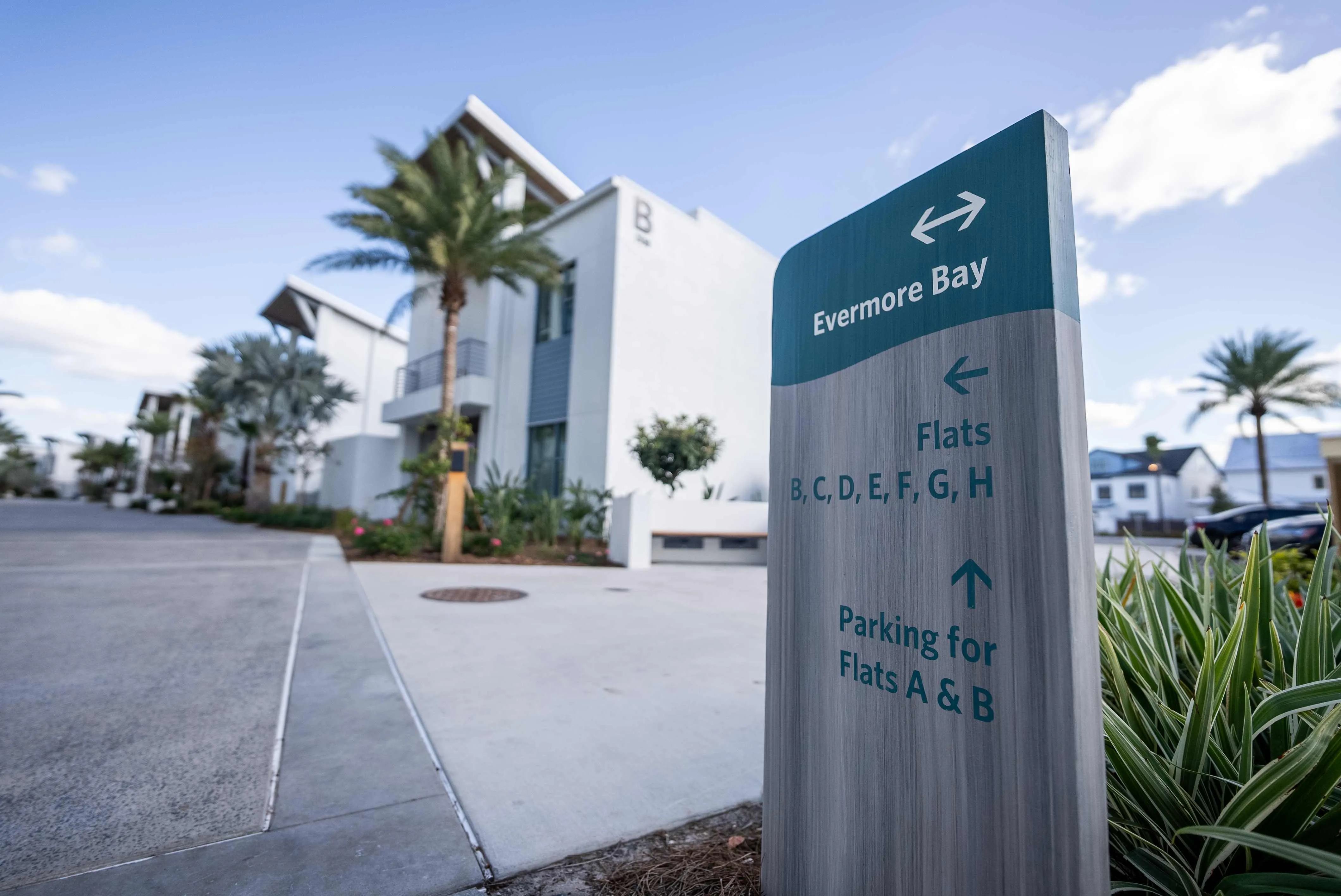 Wooden signpost directing to Evermore Bay flats B to H left and parking for flats A and B straight ahead.