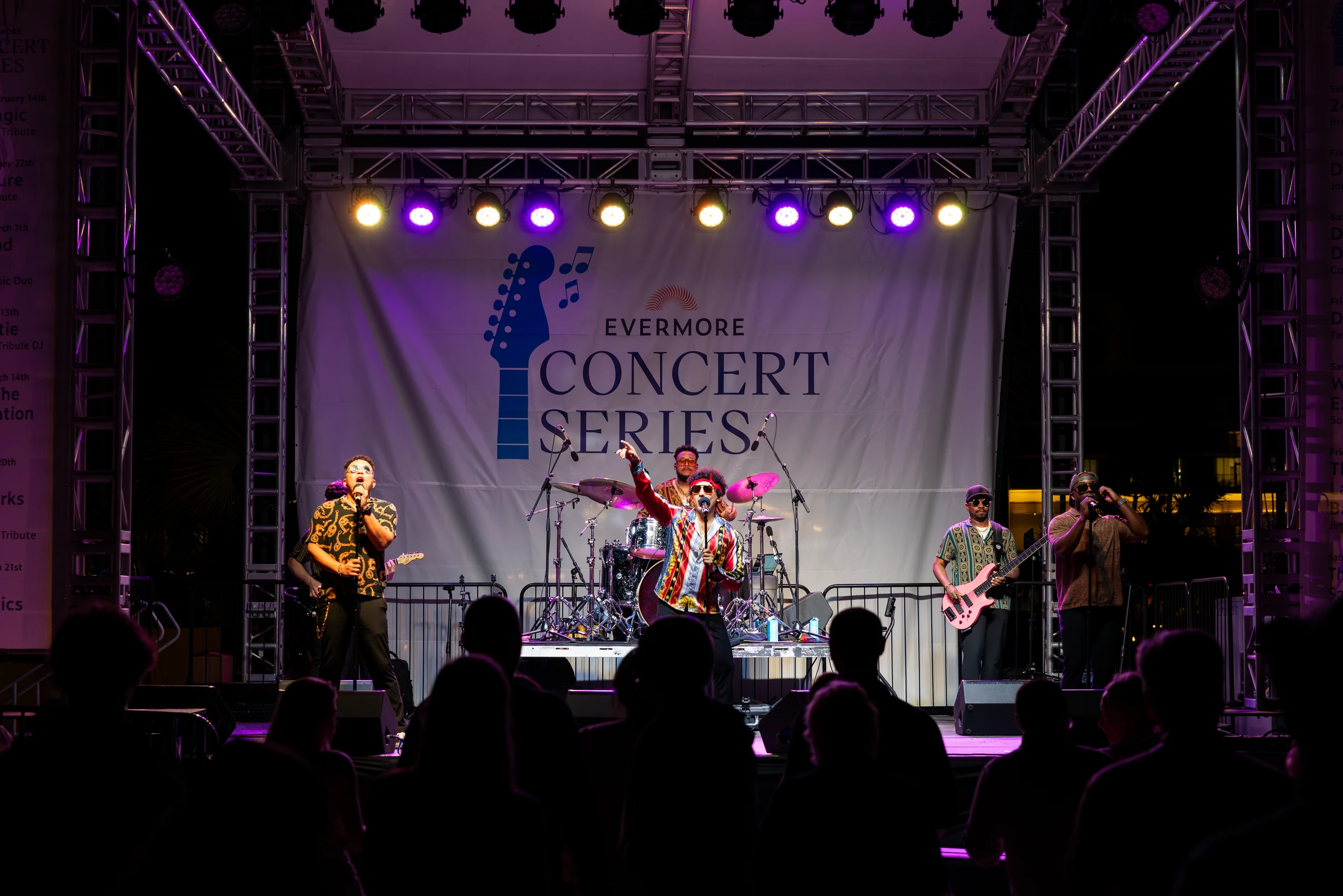 Band performing on stage at night with 'Evermore Concert Series' banner and purple-yellow stage lights.