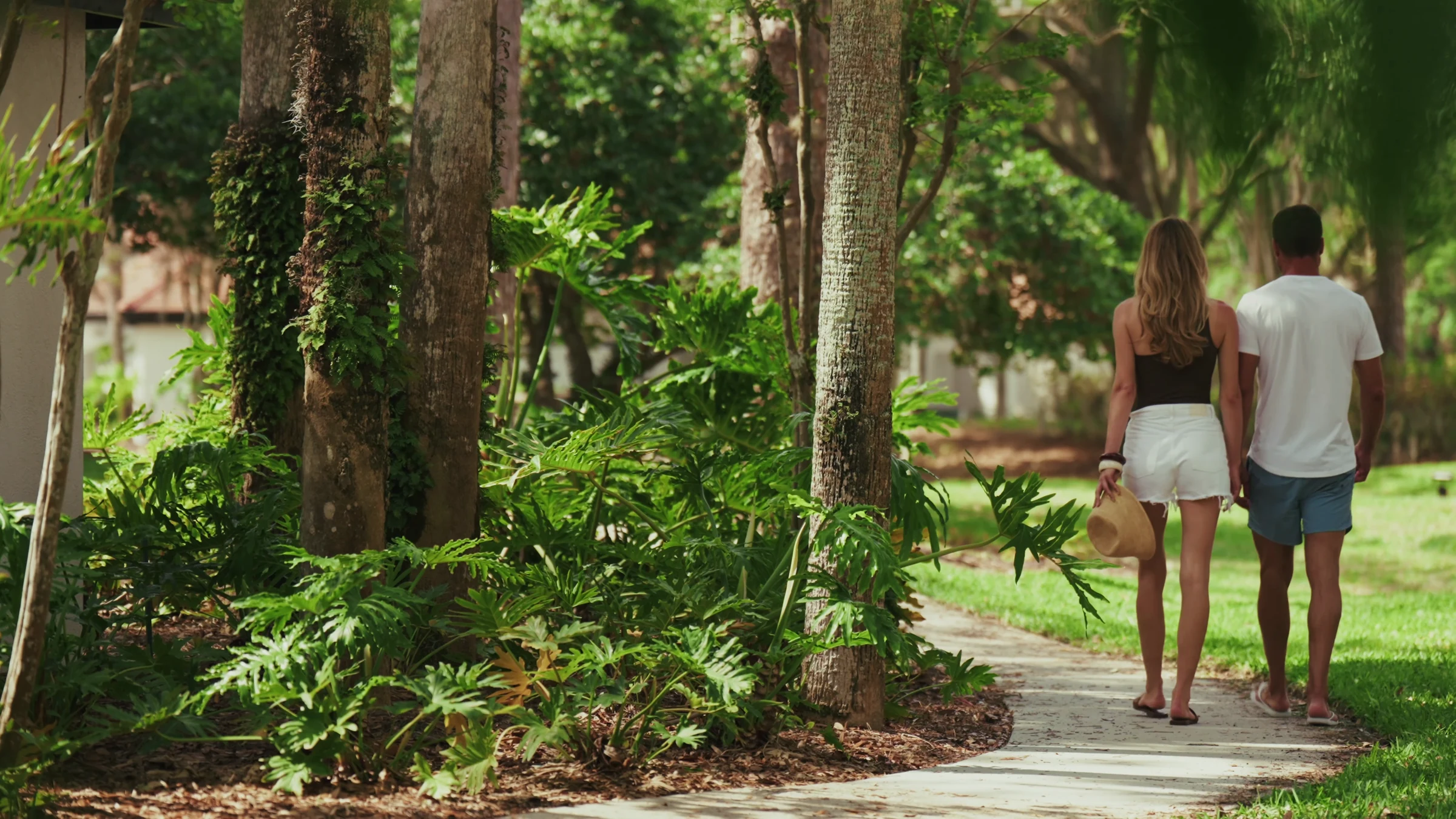 Couple walking on a curved garden path surrounded by trees and lush green plants.