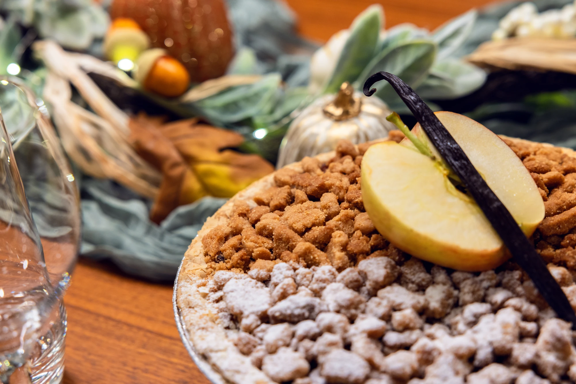 Thanksgiving dessert topped with pear slices and a vanilla bean, surrounded by autumn table decorations.