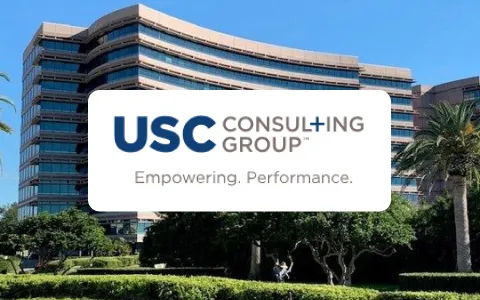 USC Consulting Group logo with slogan Empowering. Performance. on office building background.