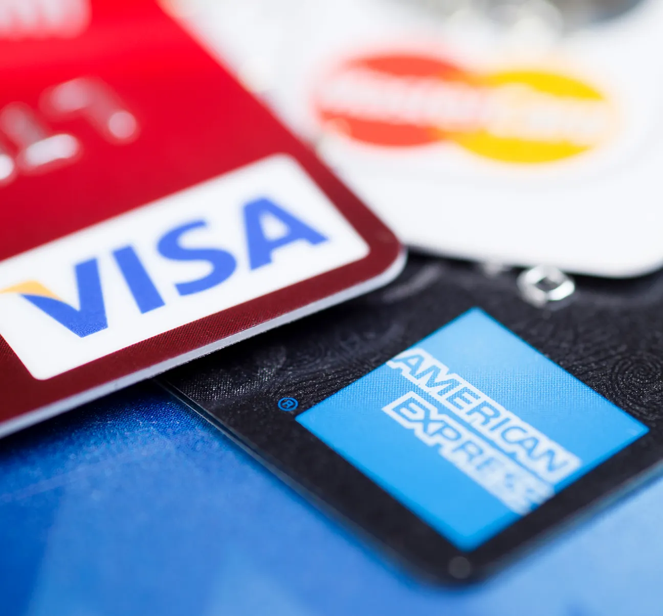 Close-up of Visa, American Express, and Mastercard credit cards overlapping each other.