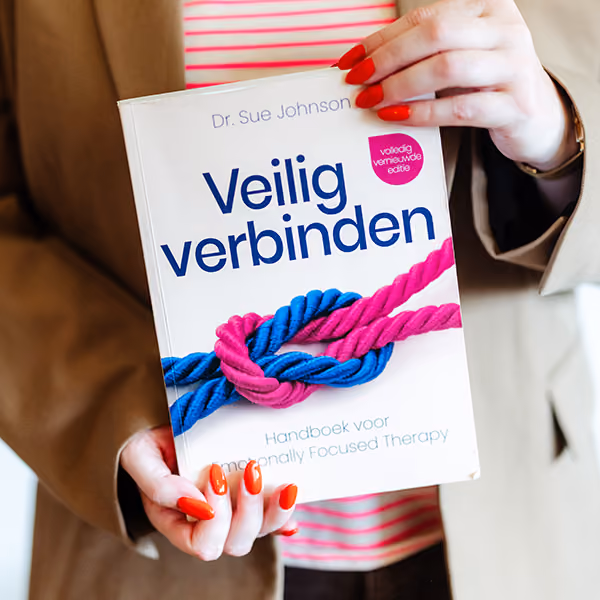 Persoon met laknagels houdt boek ’Veilig verbinden’ van Dr. Sue Johnson vast.