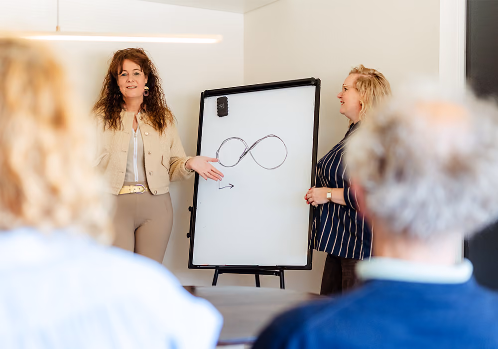 Carolien tekent een oneindigheidssymbool op het whiteboard tijdens een EFT-workshop van Voordeliefde