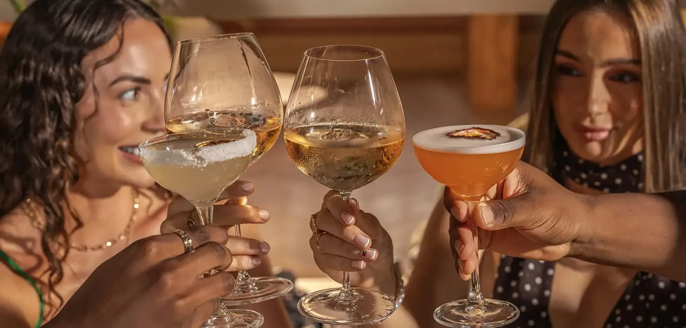 Guests clinking cocktails and glasses of wine across the table at brunch