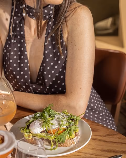 Poached egg on toasted sourdough with dressed leaves and grated cheese, served at the table