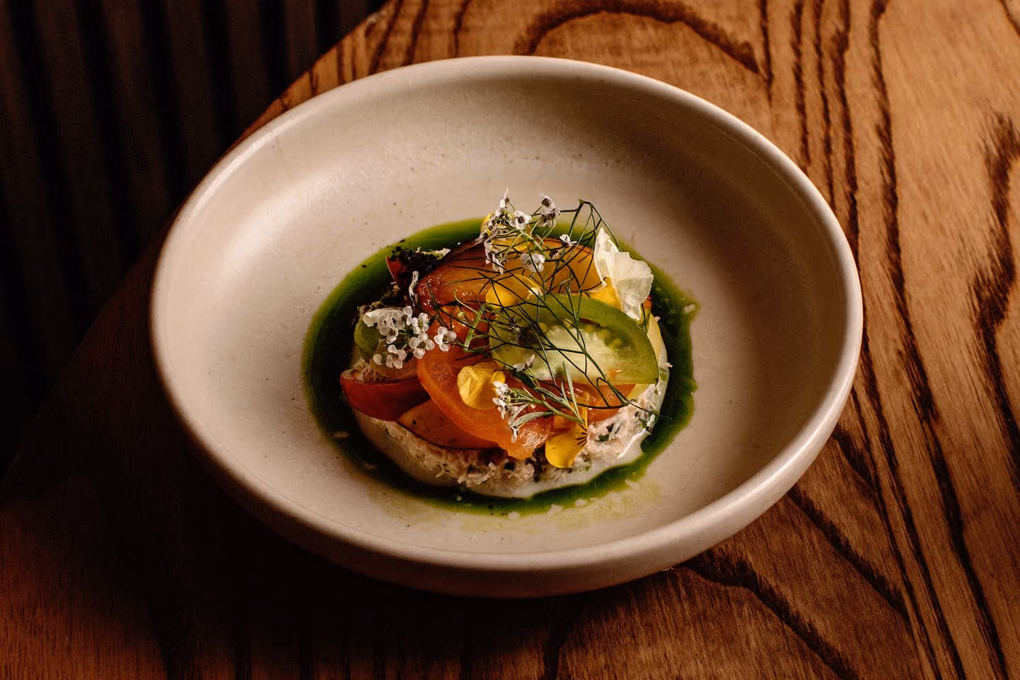 Plated gourmet seafood dish with fresh herbs and broth on a ceramic bowl.