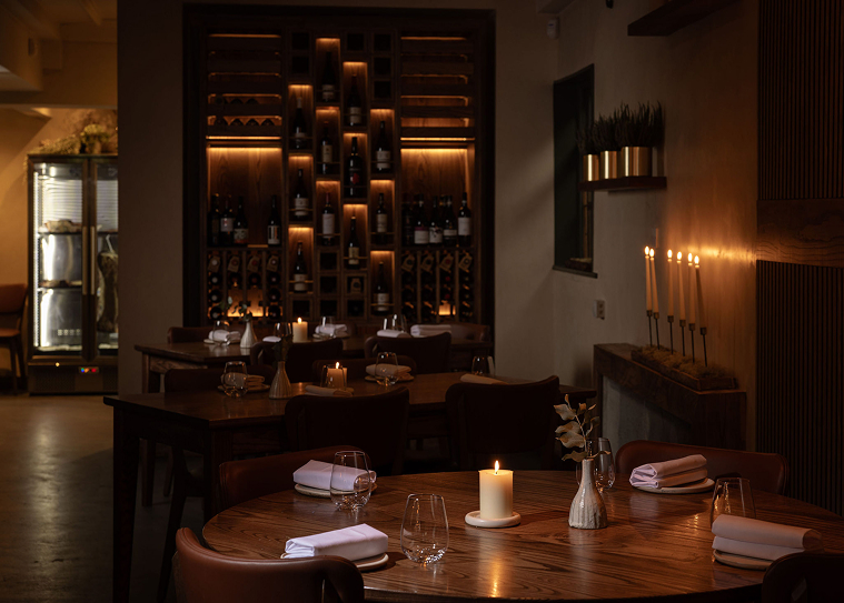 Upscale restaurant interior with red leather booths, glass pendant lights, and greenery on walls.
