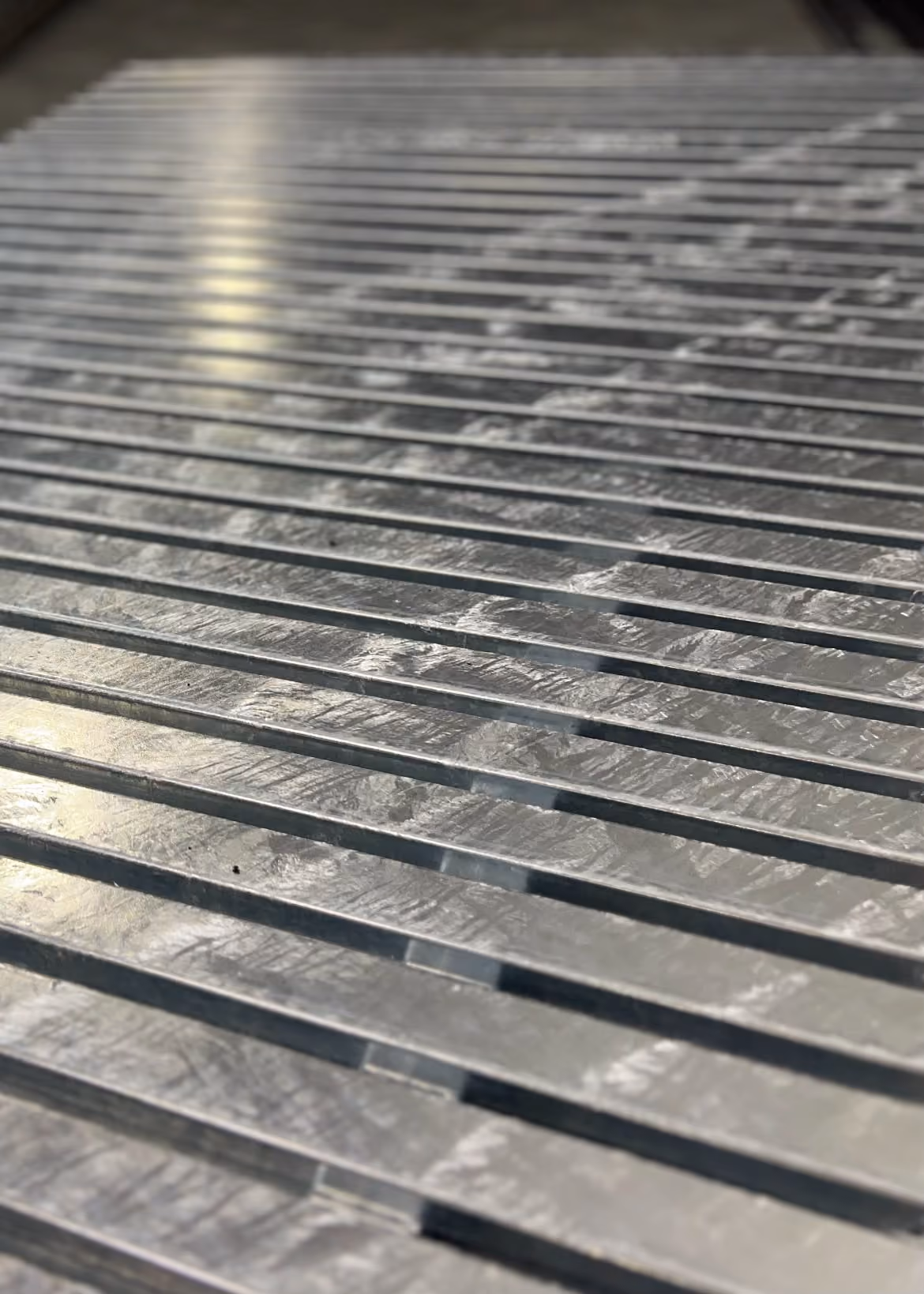 Close-up of shiny metal bars with light reflecting off their textured surfaces.