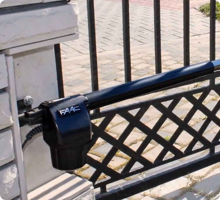 Close-up of a black FAAC automatic gate opener arm attached to a wrought iron gate.