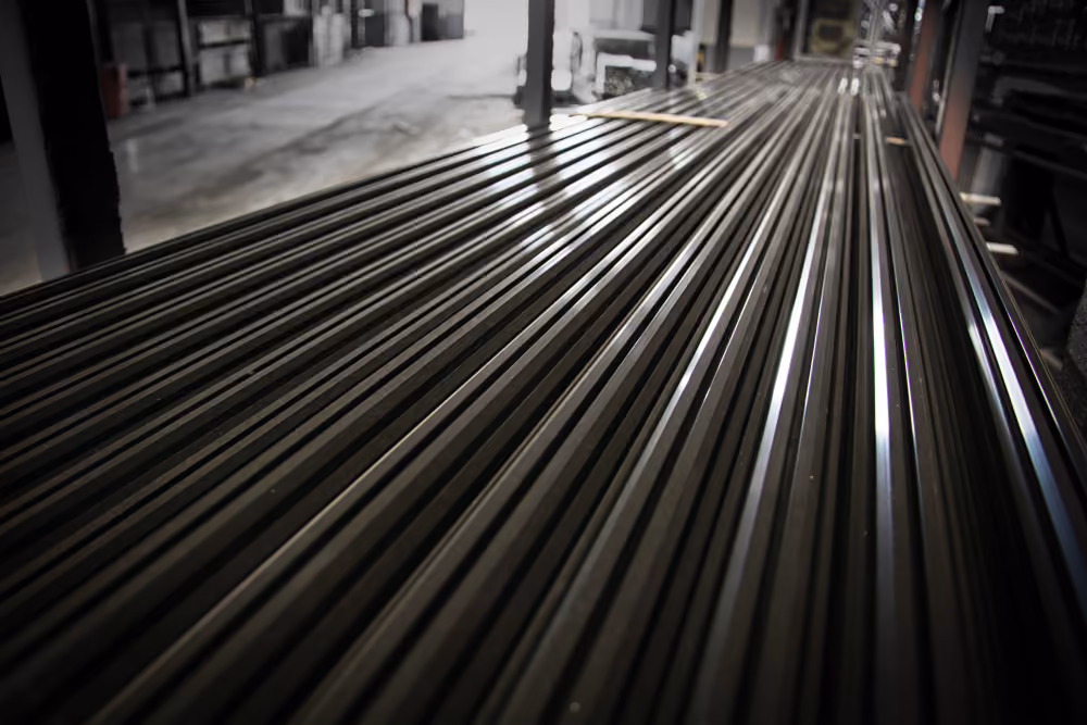 Stack of long, shiny metal rods in a warehouse or industrial setting.