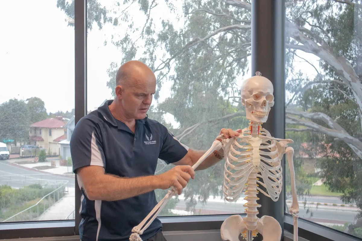Physiotherapist using a spine model to explain a disc bulge to a patient at West Coast Health Physio North Beach