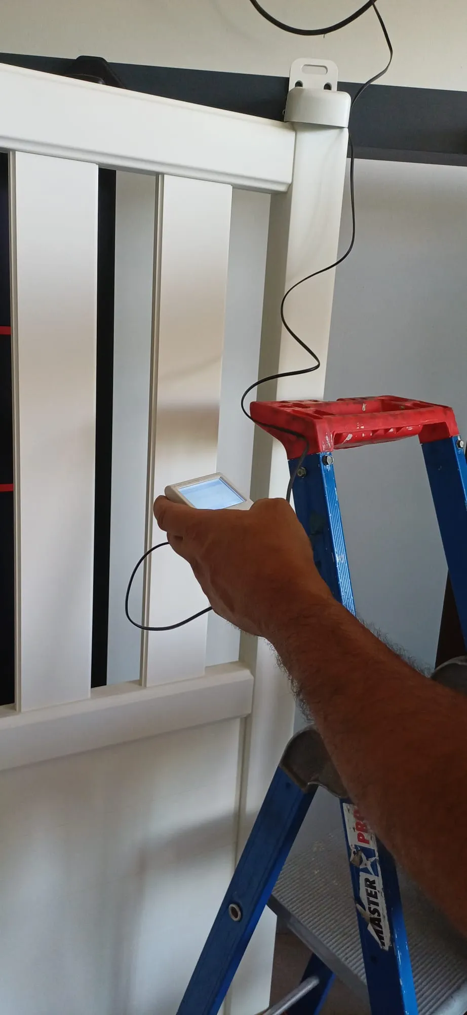 Technicien DVD Industries programmant une motorisation avec un boîtier de réglage