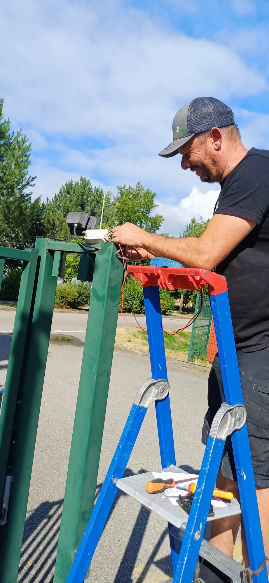 Une personne assemble des pièces sur une table avec des outils tels qu'un marteau et un cutter.