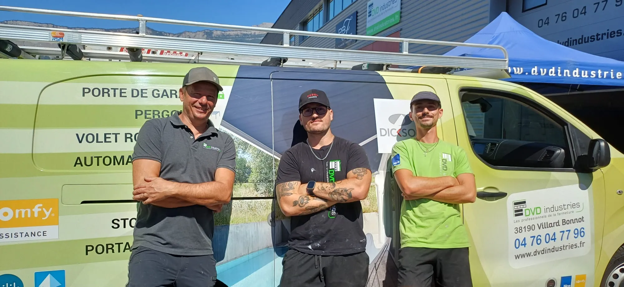 Trois hommes souriants debout devant une camionnette DVD industries avec bras croisés.